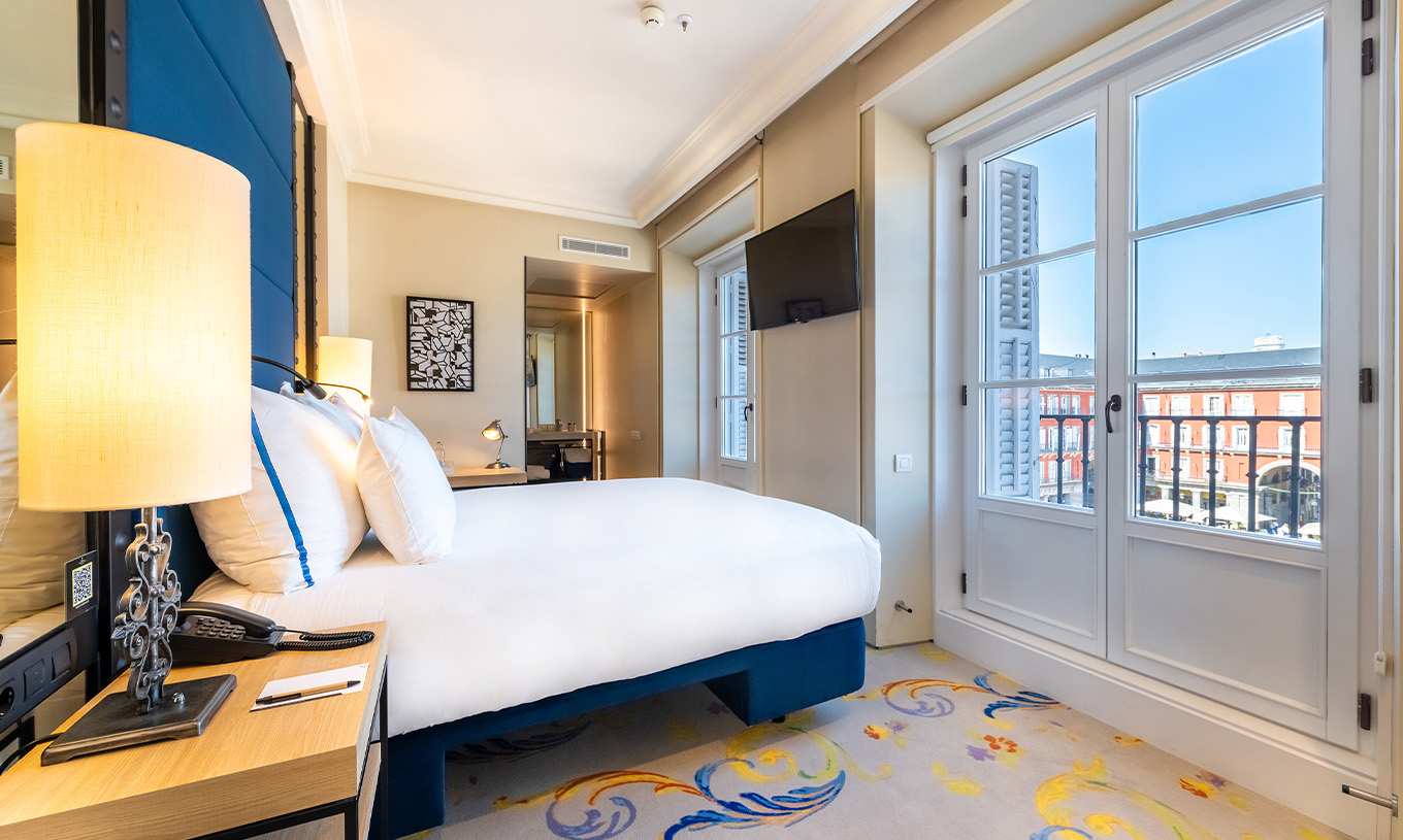 Das Deluxe Grand Plaza Mayor im Pestana Plaza Mayor Madrid hat ein Doppelbett und ein Fenster mit Blick auf die Plaza Mayor