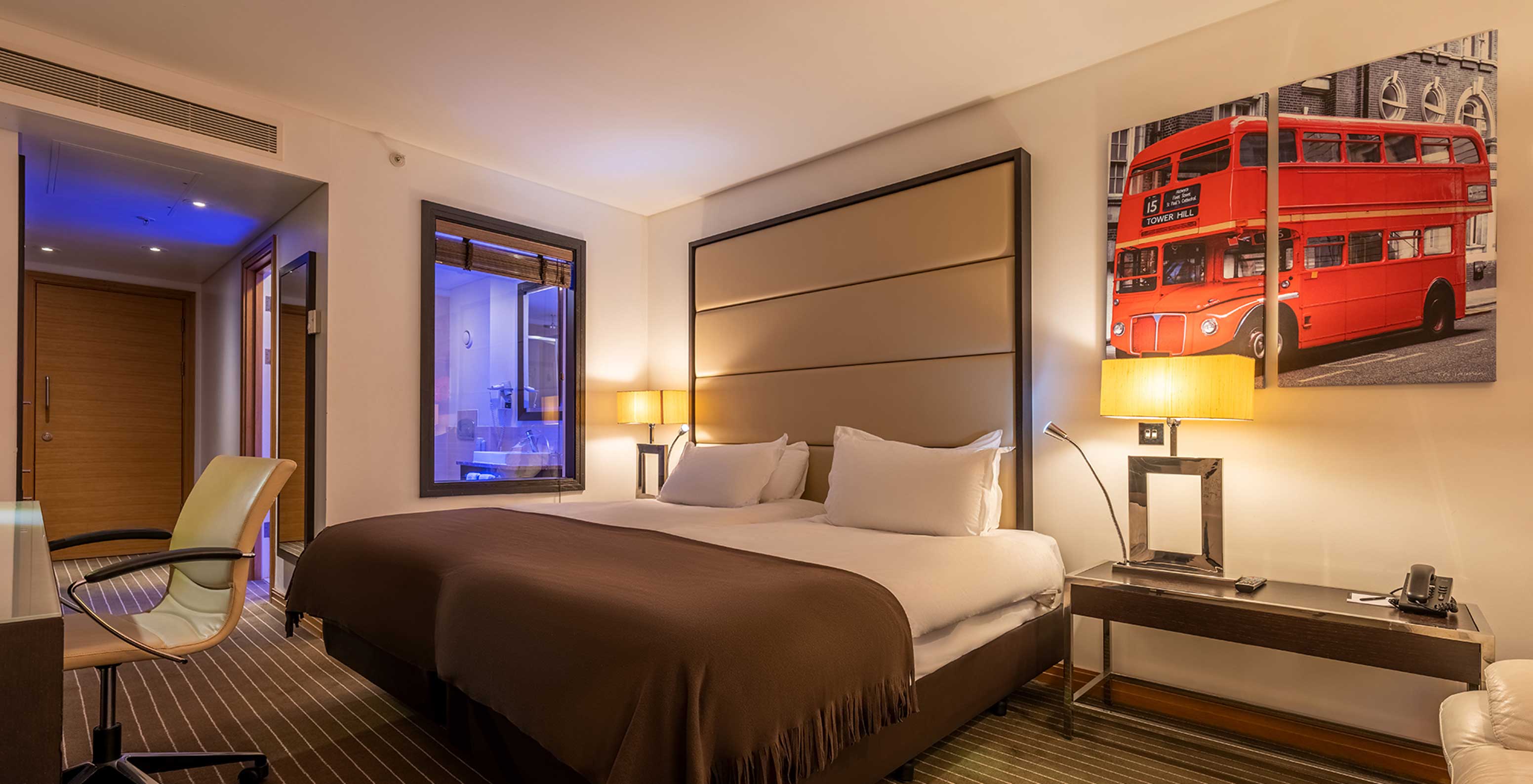 Das Premium Twin im Pestana Chelsea Bridge hat zwei Betten, London-Bilder, Nachttisch, Sofa und Stuhl