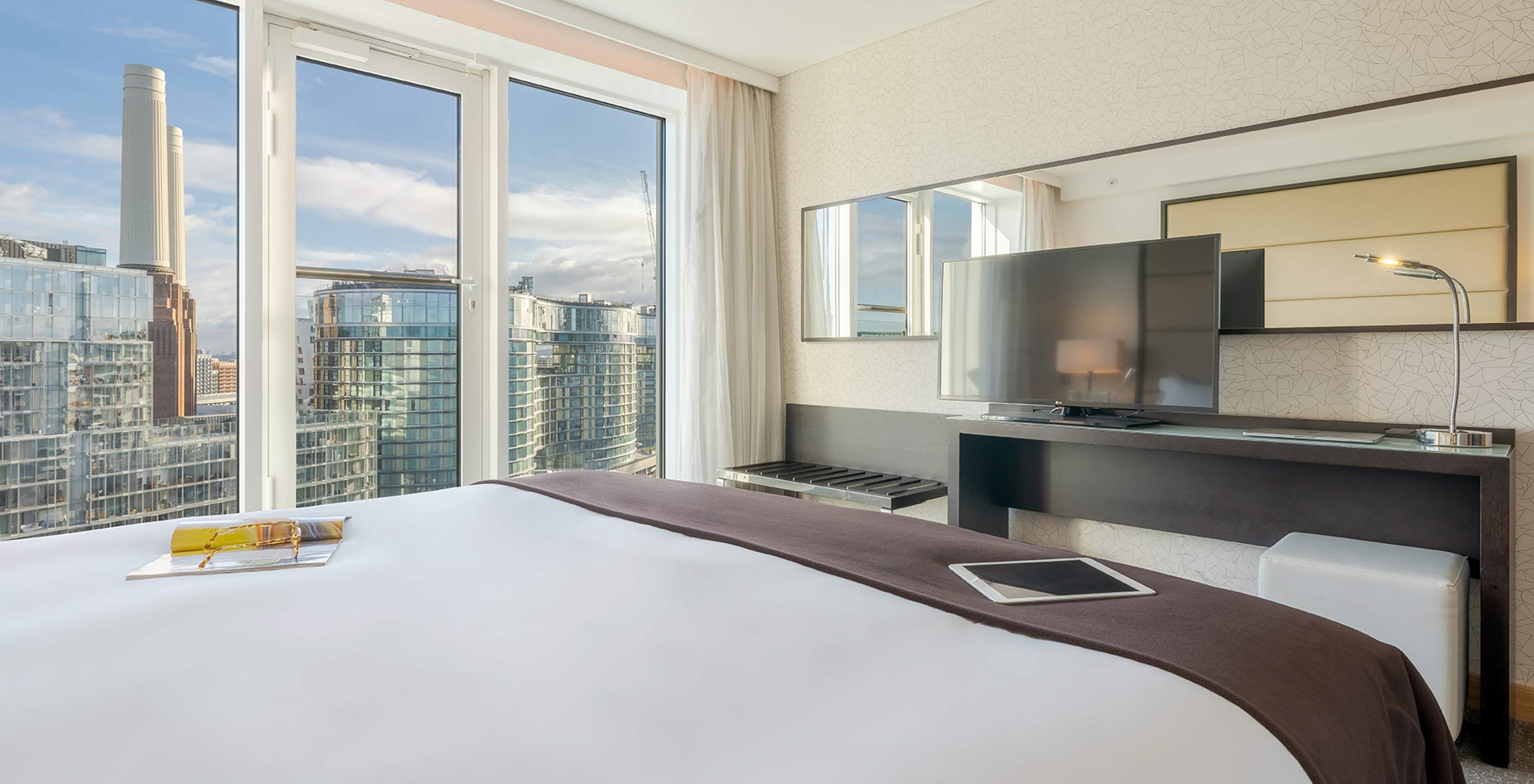 Das Superior King im Pestana Chelsea Bridge hat Doppelbett, Schreibtisch mit TV, Sofa und Fenster zur Stadt