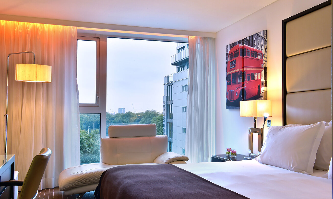 Das Premium King im Pestana Chelsea Bridge hat Doppelbett, Schreibtisch mit Stuhl, Sofa und großes Fenster mit Aussicht