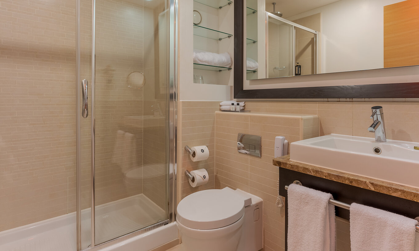 Die Executive One Bedroom Suite im Pestana Chelsea Bridge hat Glasdusche, WC, Waschbecken und Spiegel