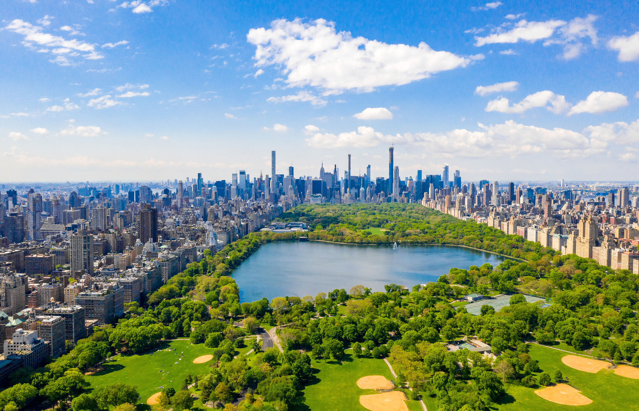 Landschaft des Central Parks in New York City, mit verschiedenen Grünflächen, baumgesäumten Wegen und Wolkenkratzern rund um den Park