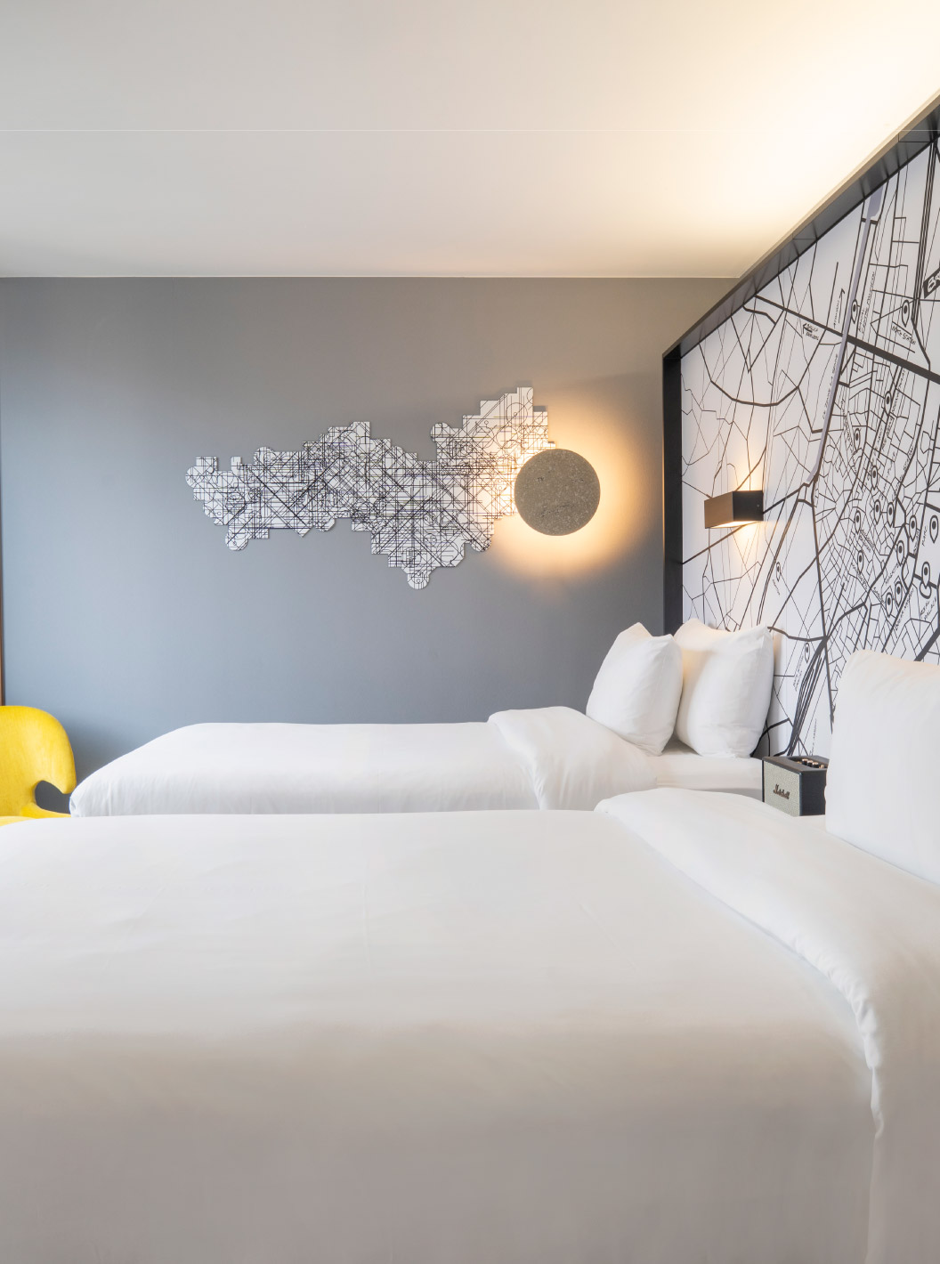 The Superior Twin at Pestana Brussels Schuman has two single beds, a yellow chair, and a window with a view