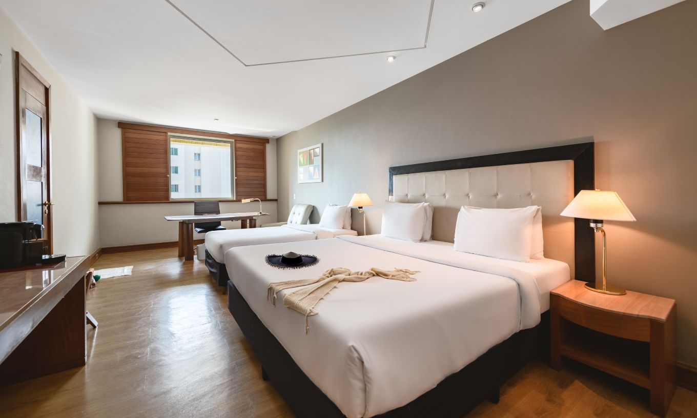 The Deluxe at Pestana São Paulo has a double bed, two bedside tables, a desk, and a window