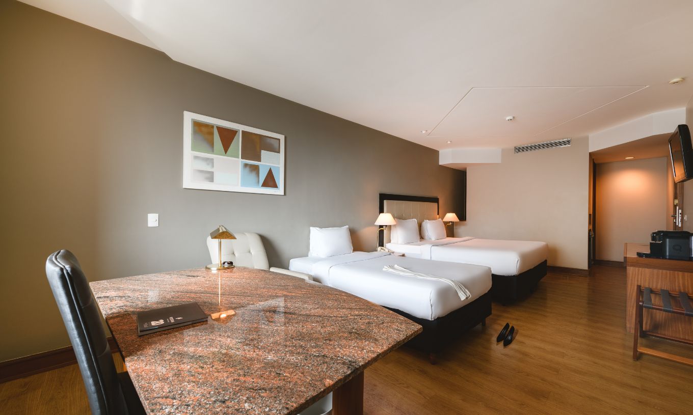 The Family Room at Pestana São Paulo has a stone desk, a double bed, and a single bed