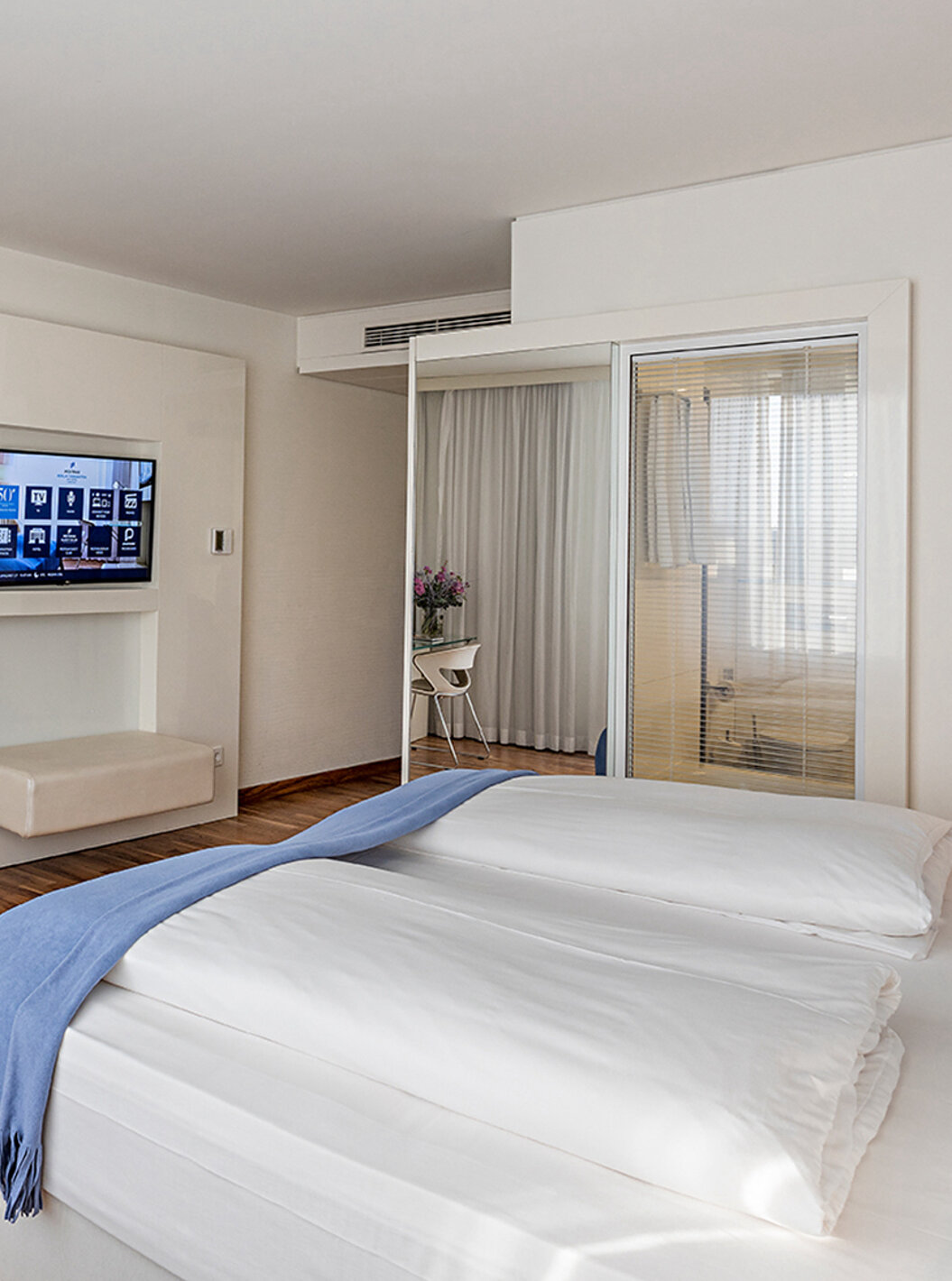 Deluxe room at Pestana Berlin Tiergarten has a TV, a desk with lamp and chair, sofa and armchair