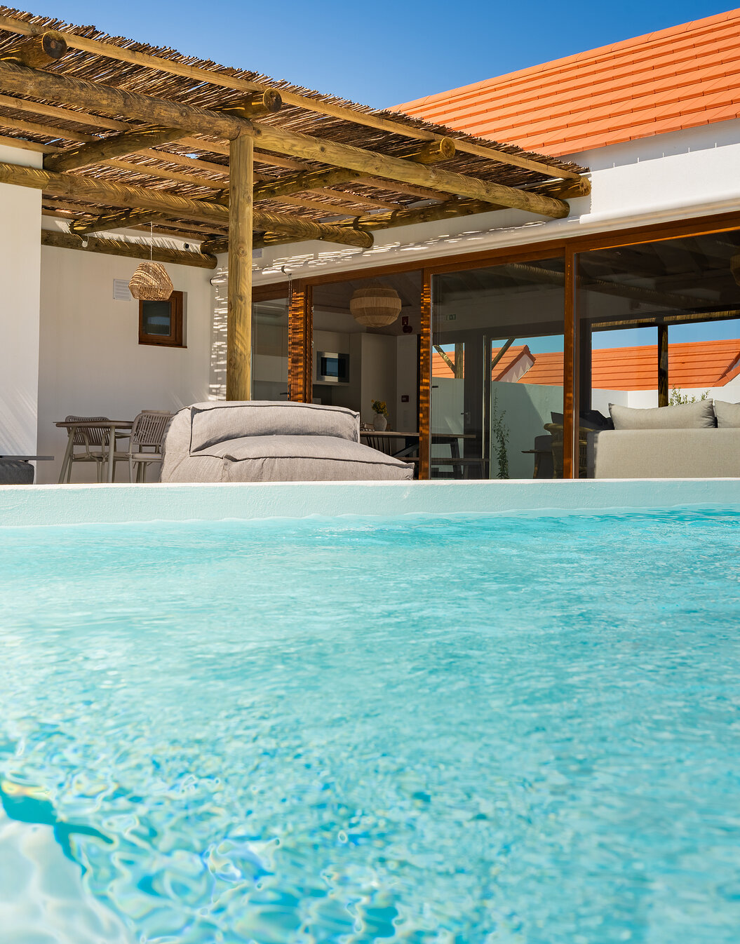 Outdoor area of a villa at Pestana Comporta Village Residences, featuring a crystal-clear blue pool and seating area
