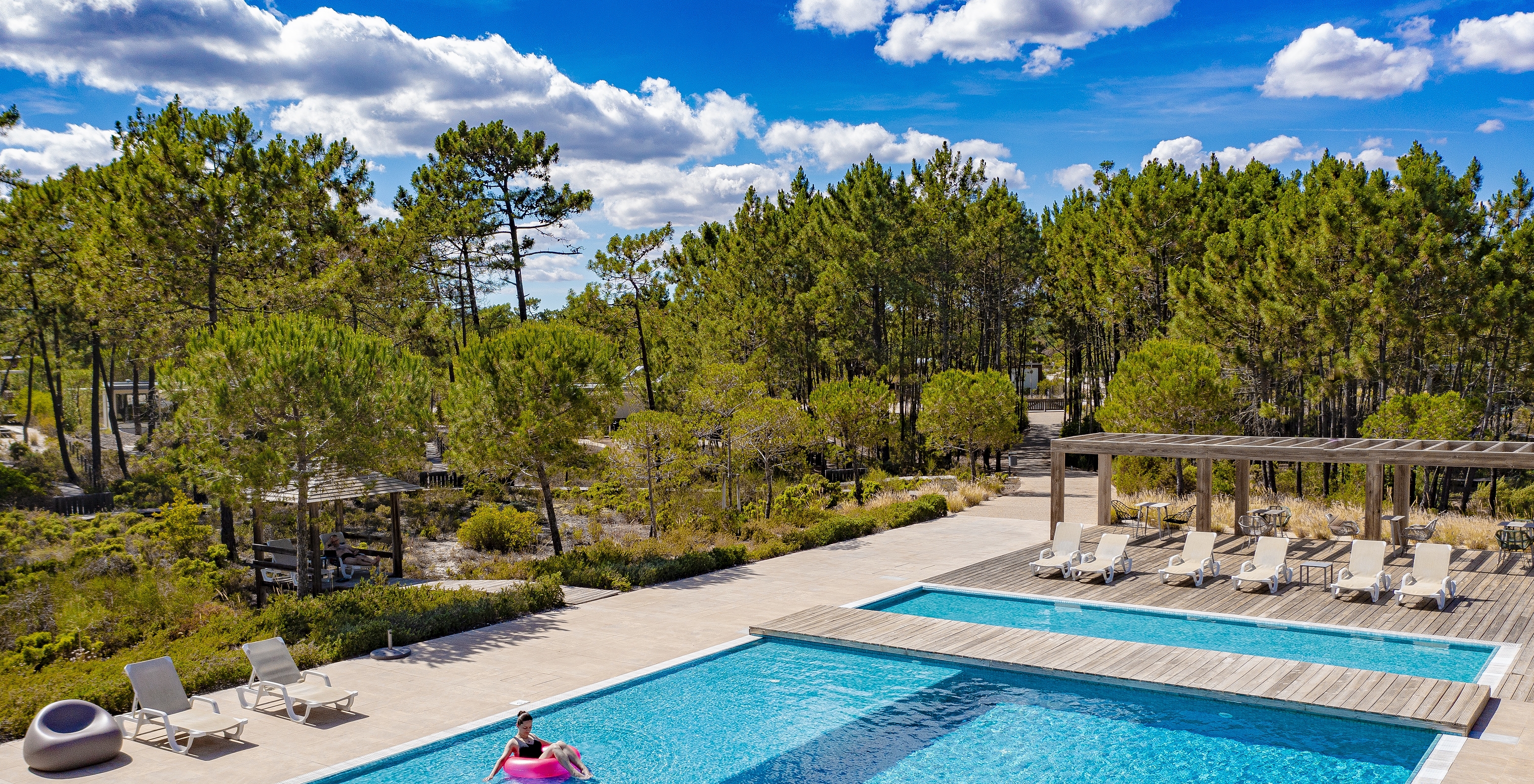 Outdoor pool at Pestana Tróia Eco Resort, with a woman relaxing on a pink float in the pool