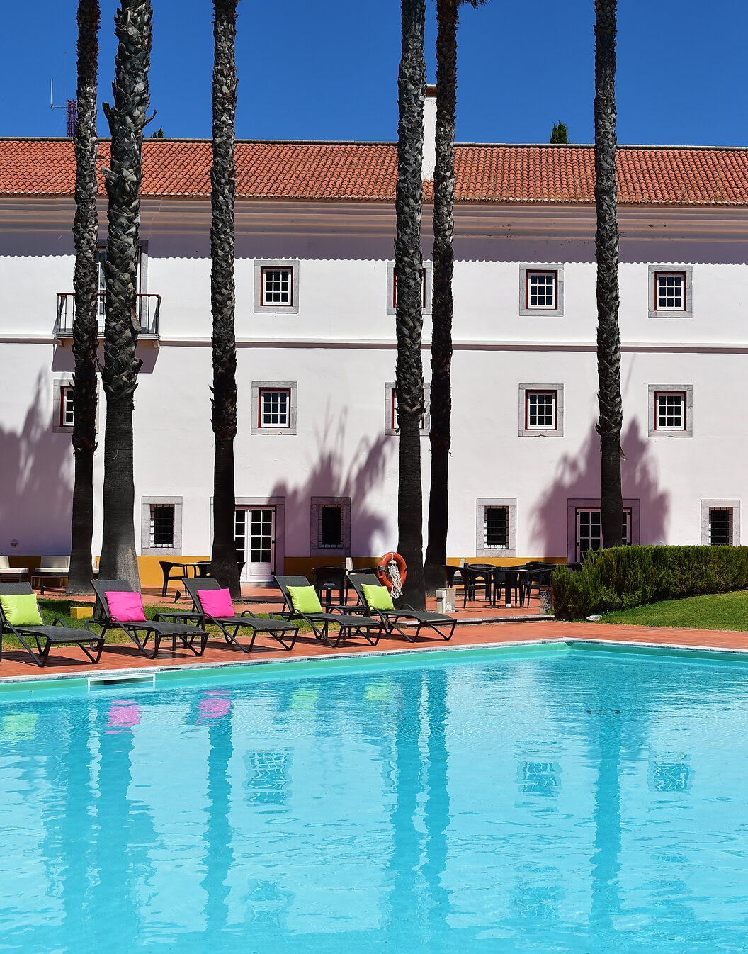 Outdoor pool of Pousada Convento Beja, a historic hotel in Alentejo, with several sun loungers with cushions