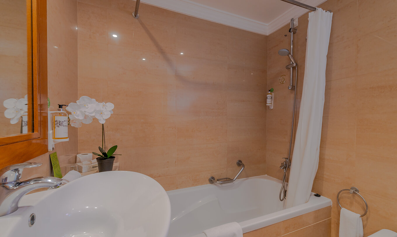 The T0 - Studio at Pestana Alvor Park has a bathroom with a bathtub with a curtain, a sink, and a flower
