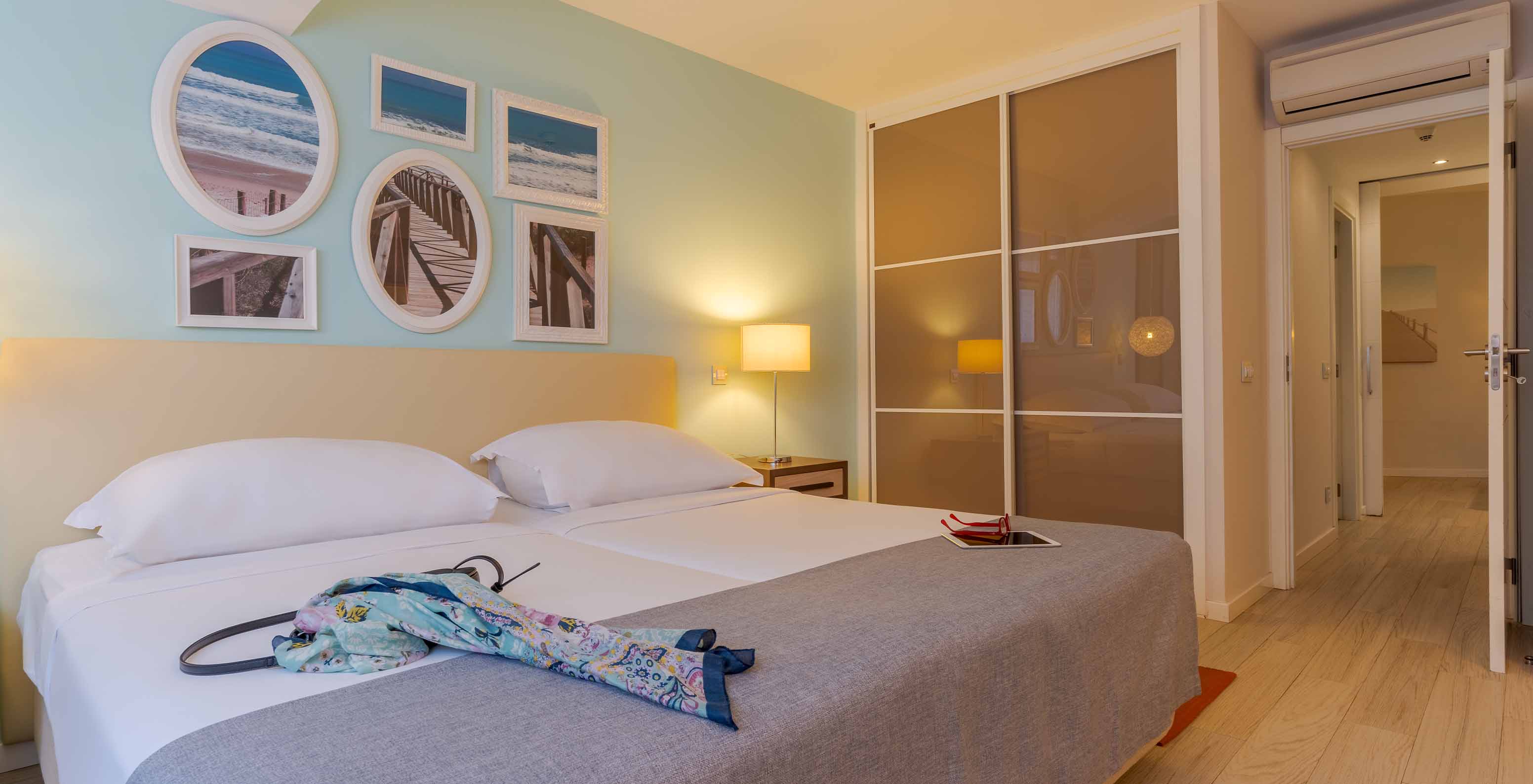 The Duplex Sea View Suite T2 at Pestana Alvor Praia has two joined beds, a wardrobe, and wall art