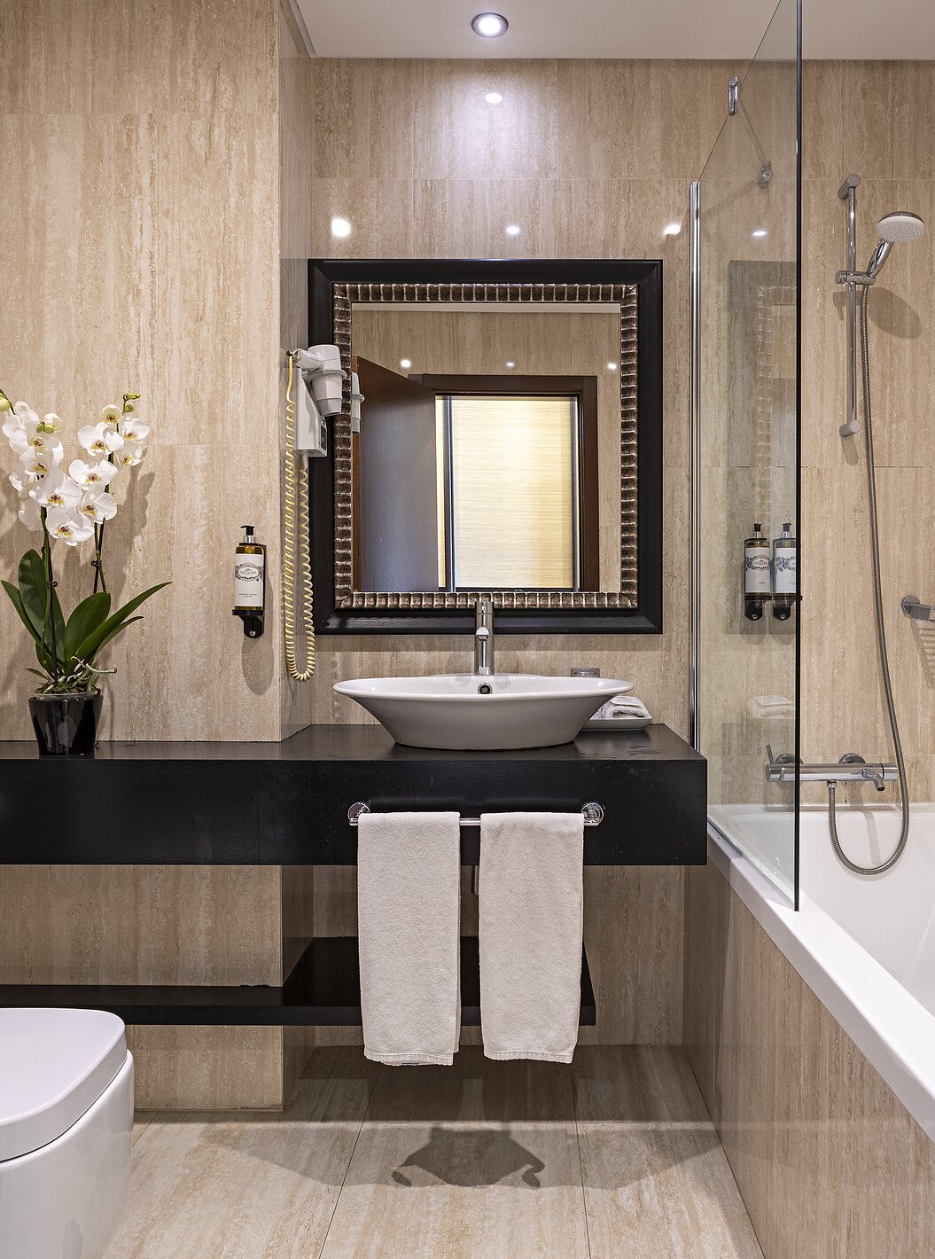 The Cliff Family at Pestana Alvor Praia has a modern bathroom with a bathtub, a sink, a toilet, a mirror, and flowers