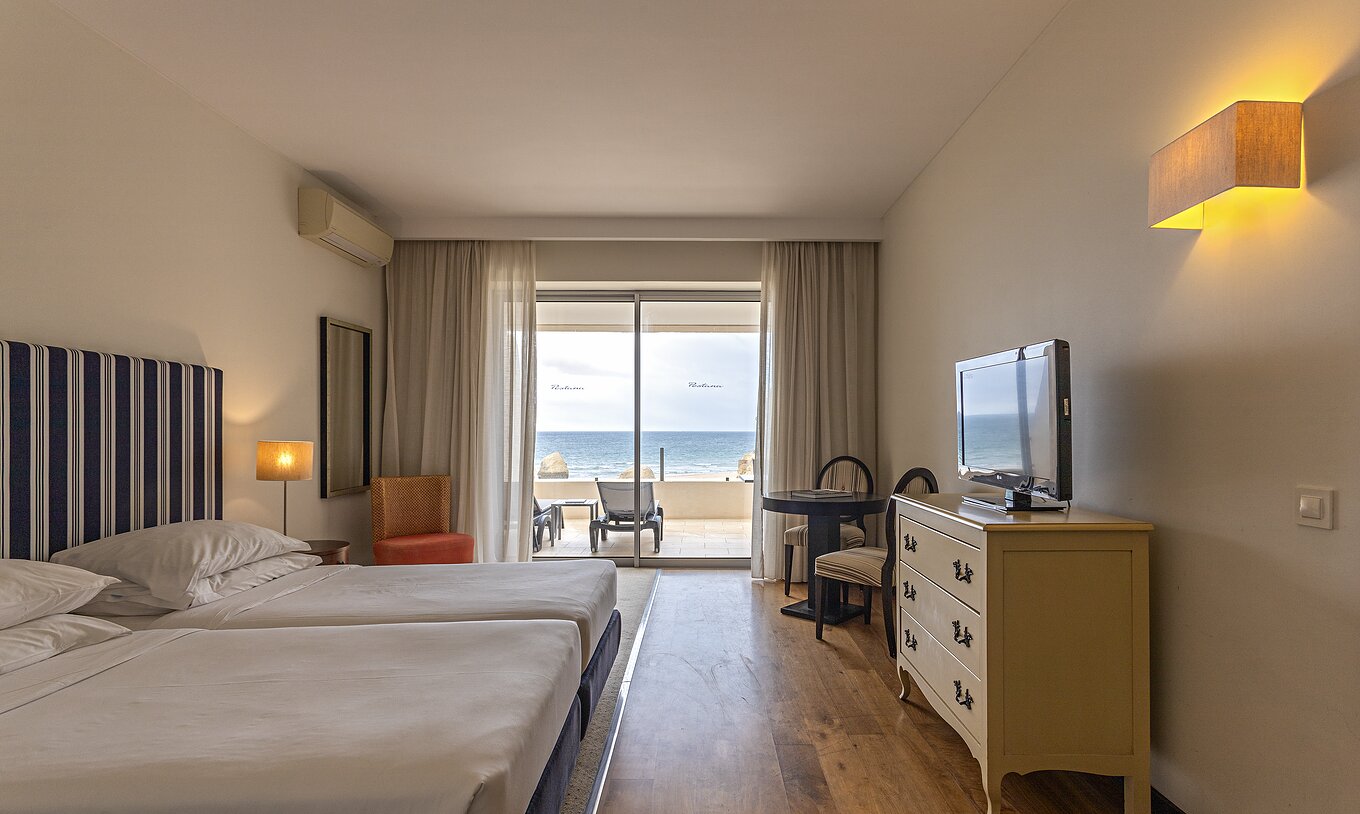 The Cliff Suite T1 at Pestana Alvor Praia has a double bedroom with a dresser, a television, and a balcony with a view