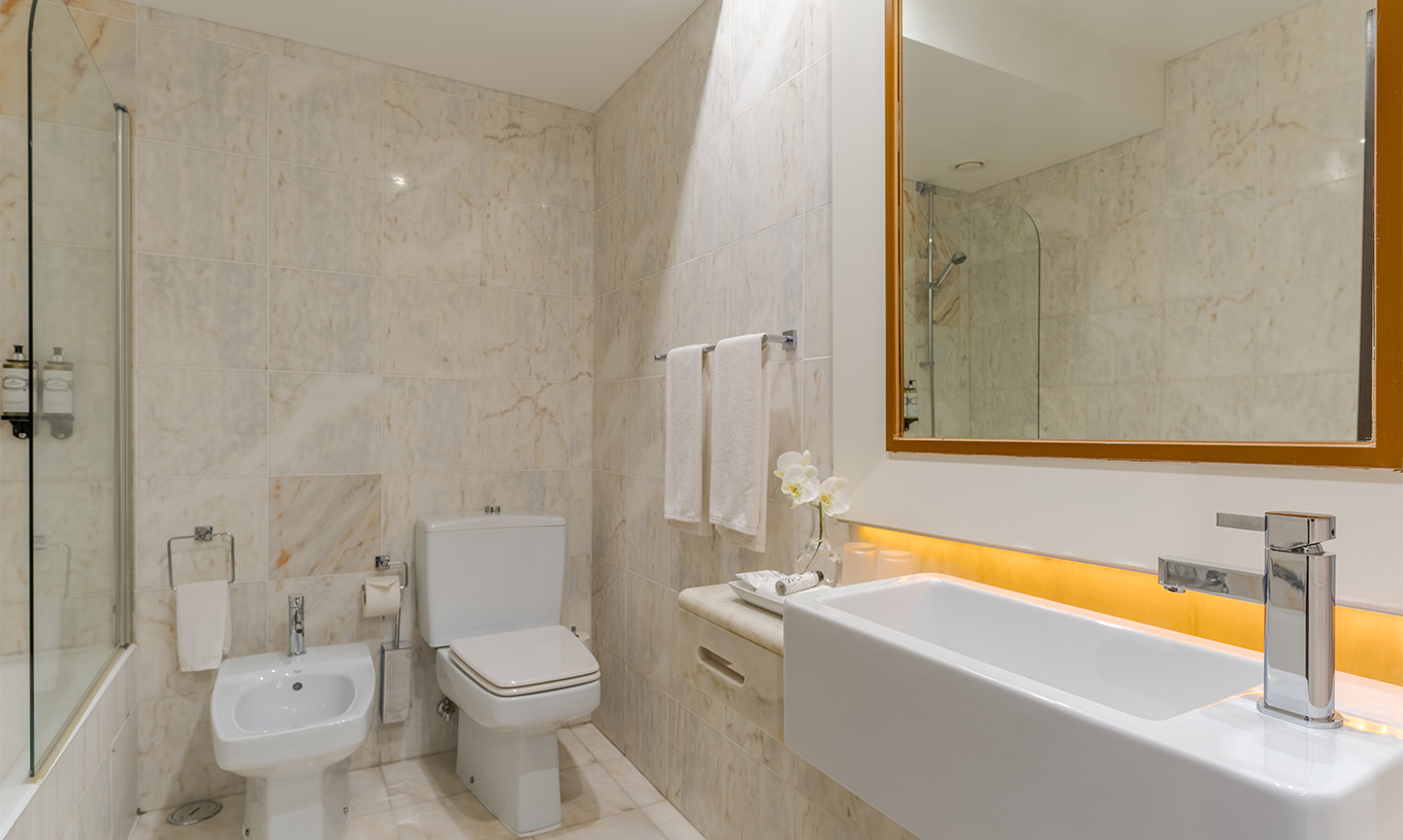 The Garden View Deluxe at Pestana Alvor Praia has a marble bathroom with a sink, mirror, toilet, and bathtub