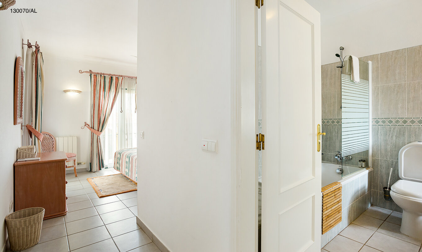 The Pestana Carvoeiro Golf T2 Superior Apartment has a bedroom with a bathroom and a wooden drawer unit