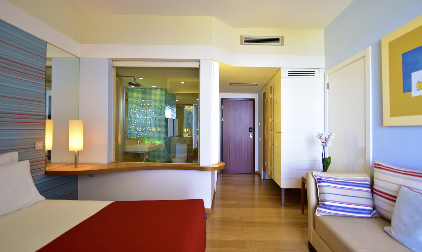 The Deluxe Sea View at Pestana Dom João II has a double bed, bedside table, and a wardrobe for clothes