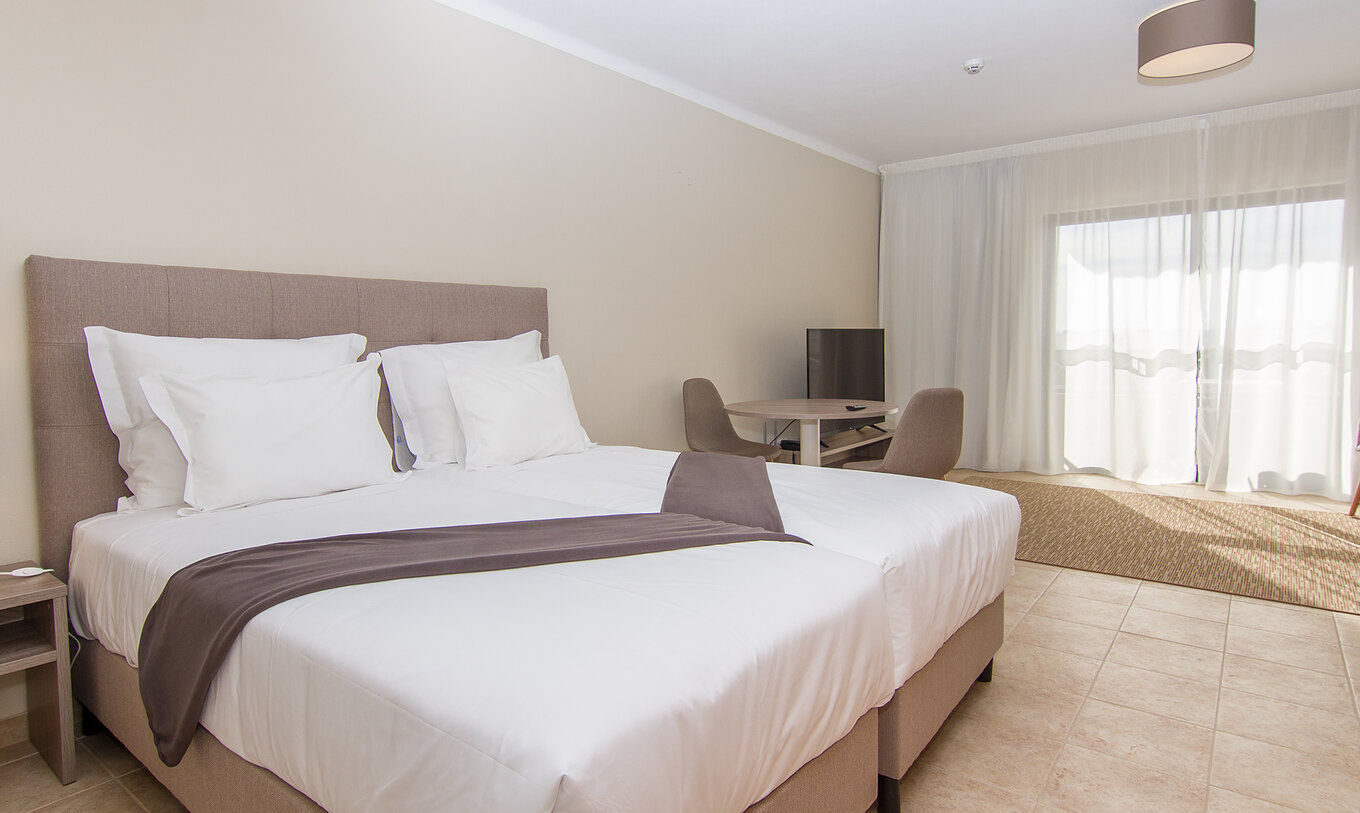 The Studio at Pestana Gramacho Residences features two single beds, a table with two chairs, and a window