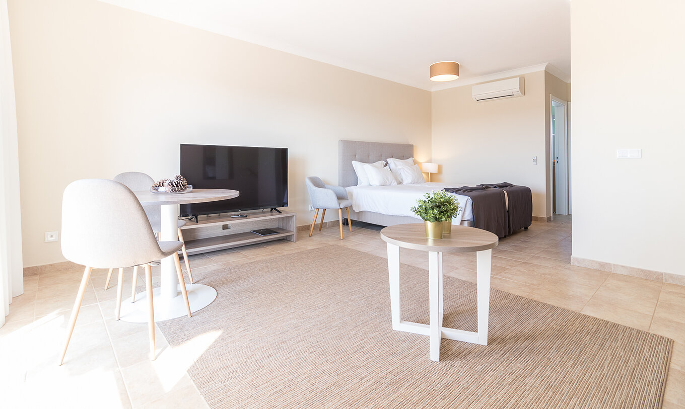 The studio at Pestana Gramacho Residences is modern with bed, TV, dining table and minimalist decor