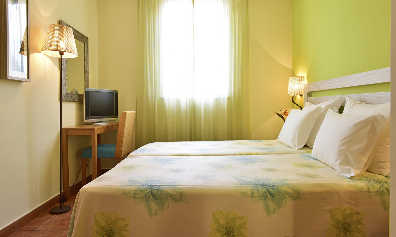 The Suite at Pestana Viking features two single beds with lamp, bedside table, television, and mirror