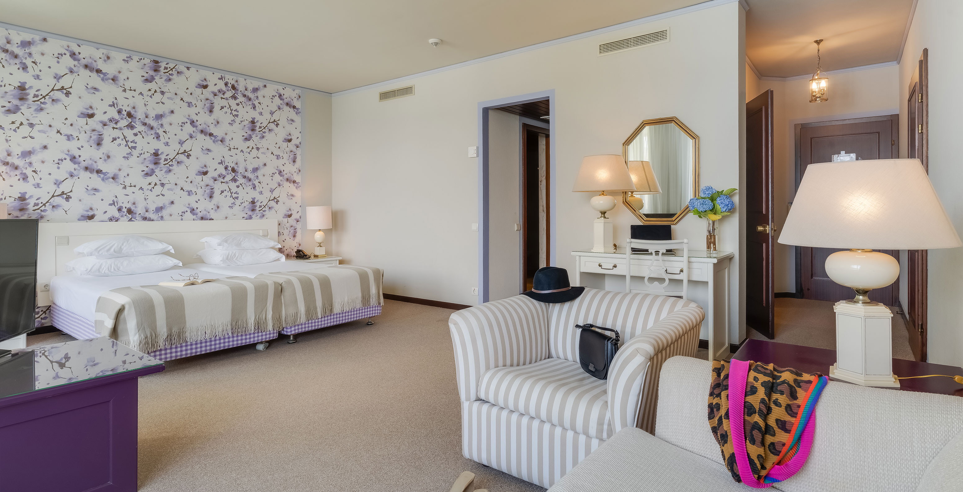 In the Junior Sea View Suite at Pestana Bahia Praia, beds are next to the balcony, with views of gardens and sea