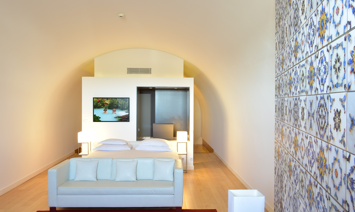 The Junior Suite Art District at Pestana Cidadela Cascais has a double bed with a white sofa and a painting on the wall