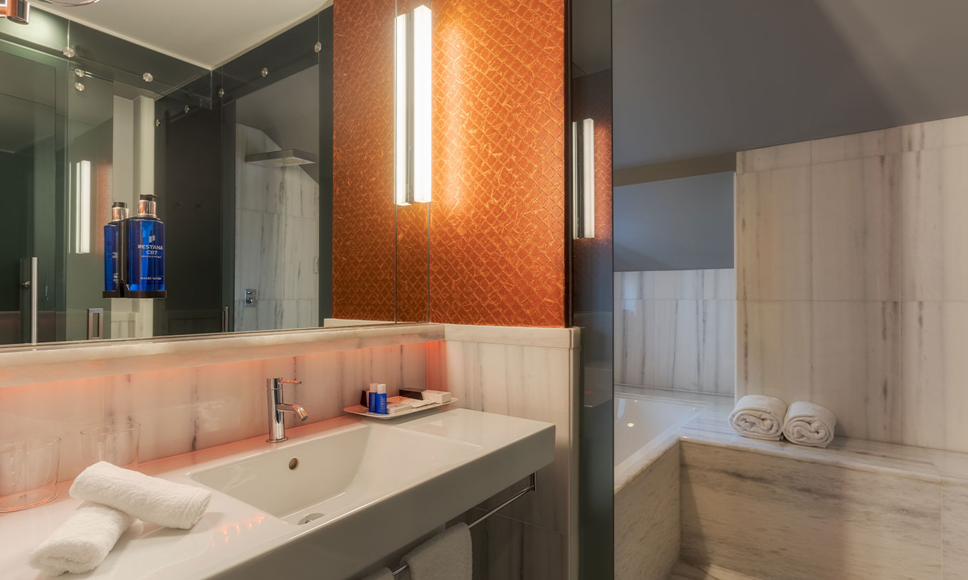 The CR7 Suite at Pestana CR7 Lisboa includes a bathroom with mirror, sink, and bathtub with shower