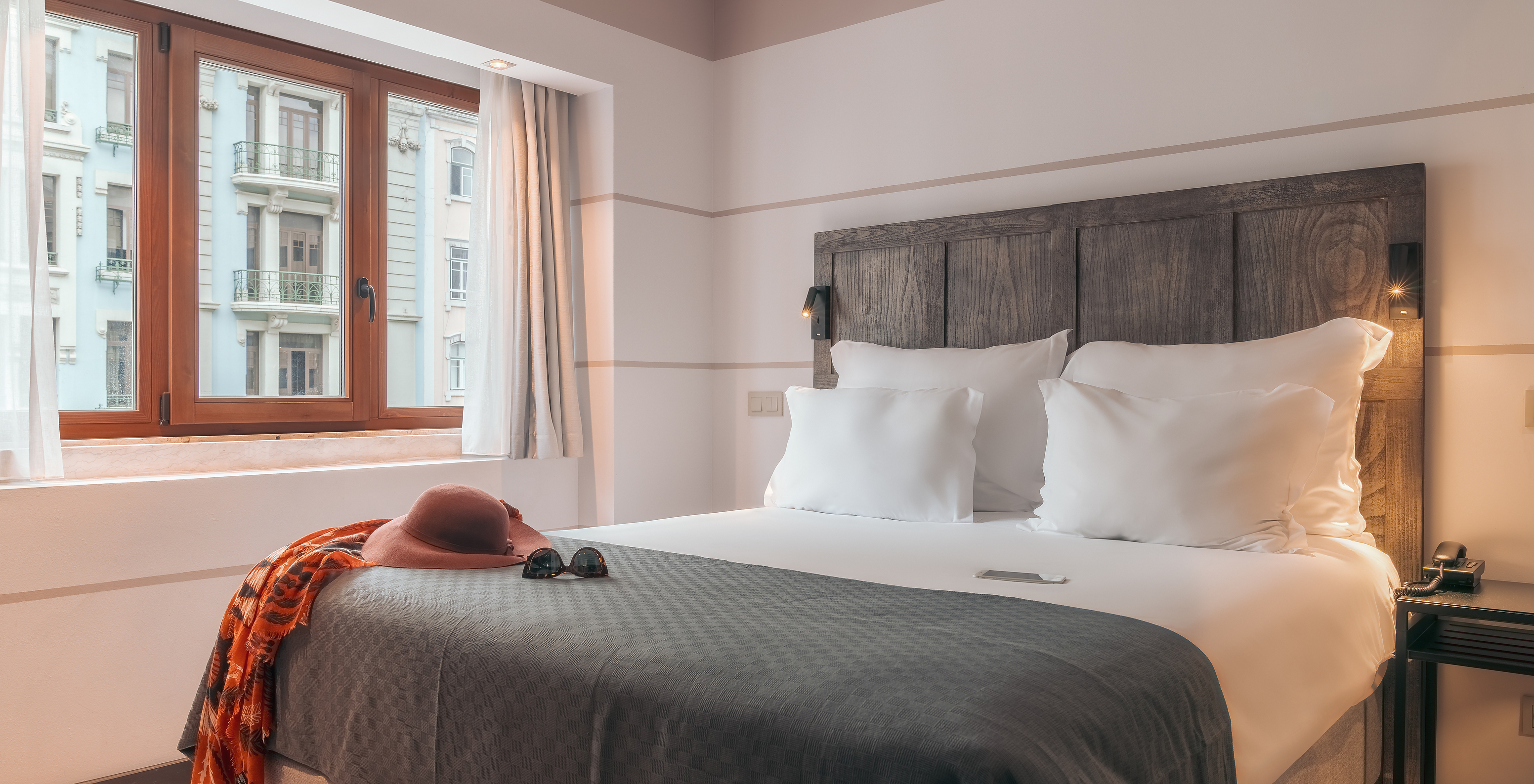The Double Classic Room at Pestana Lisboa Vintage has a double bed with headboard and gray blanket and a wooden window