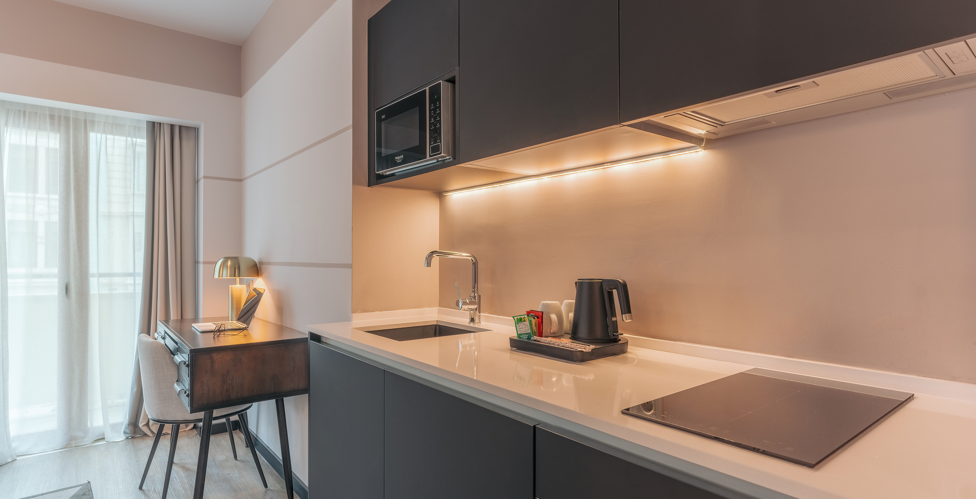 The Junior Suite at Pestana Lisboa Vintage has a kitchen unit with stove, microwave and a desk with chair