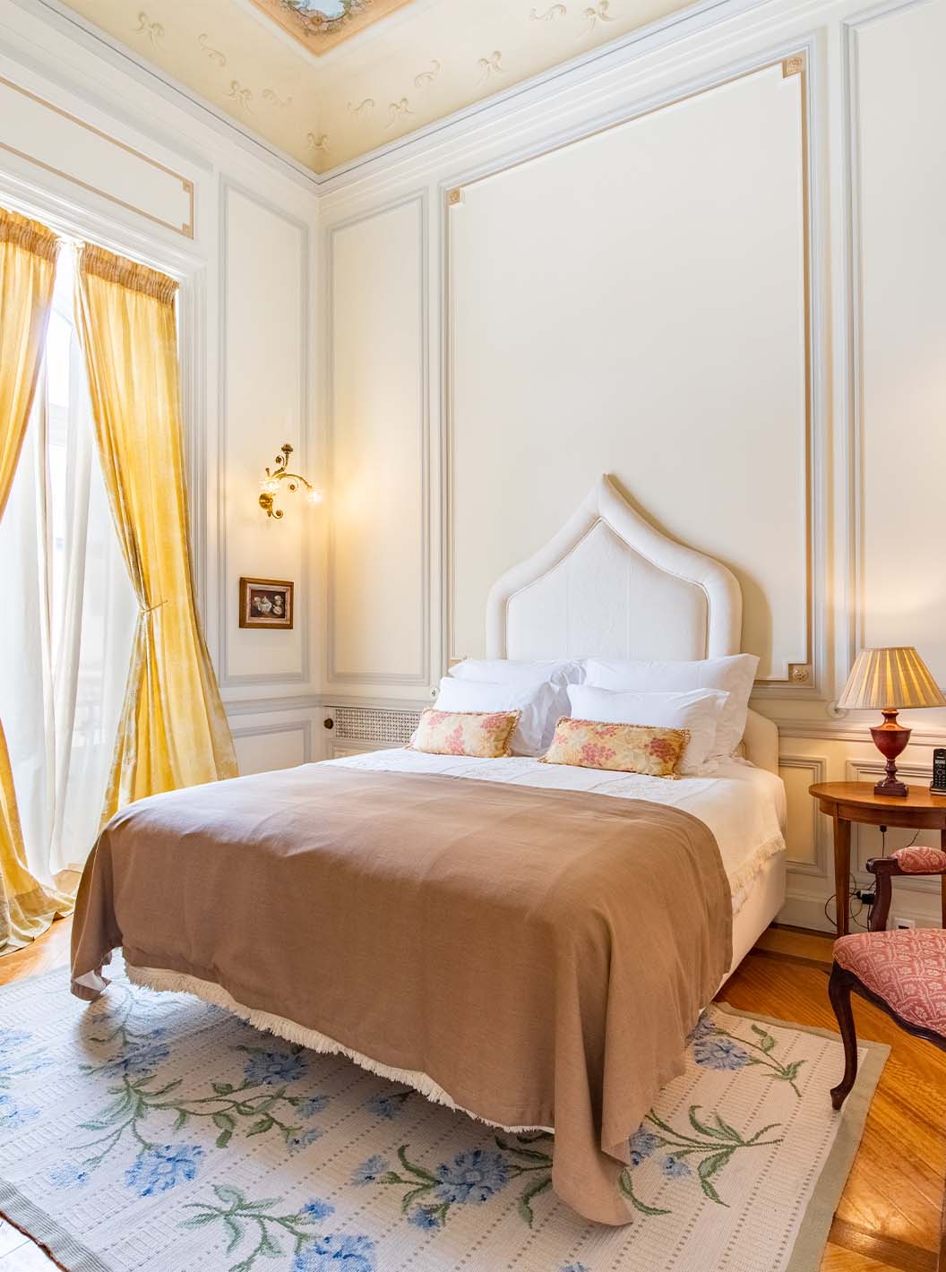 The Suite D. Amélia at Pestana Palace Lisbon has a double bed, a wooden bedside table, a chair, a rug, and a window