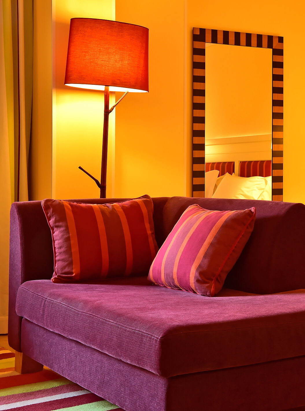 The Junior Suite of Pestana Sintra Golf has a double bed, a mirror on the wall, and a small red sofa