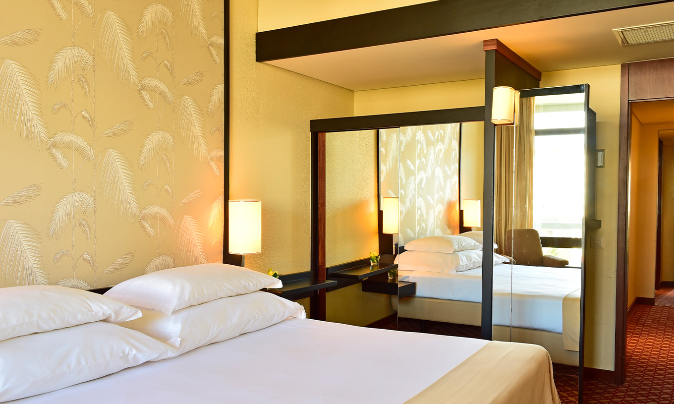 The Side Sea View Suite at Pestana Casino Park has a mirrored wardrobe next to the double bed