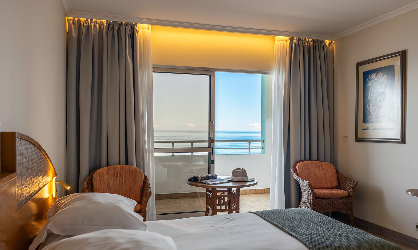 The Pestana Ocean Bay All Inclusive Classic Sea View has a double bed, two chairs, and a balcony with sea view