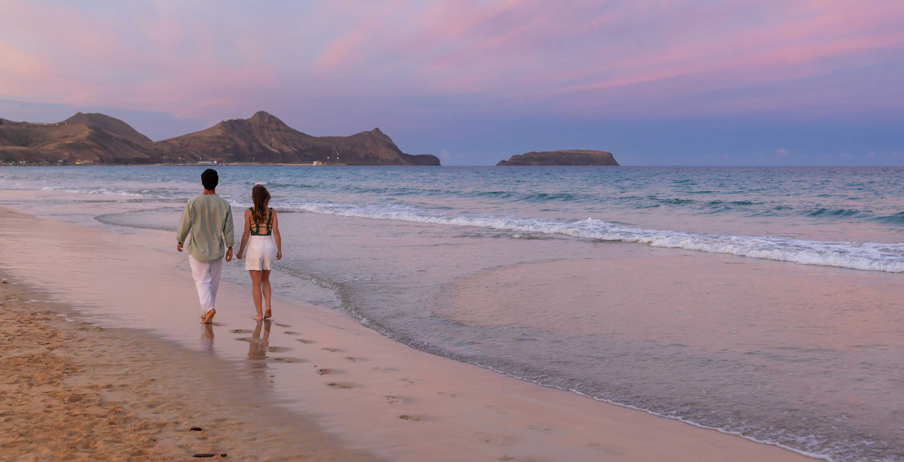 A couple walking by the sea on the beach of Porto Santo island, in front of Pestana Porto Santo All Inclusive