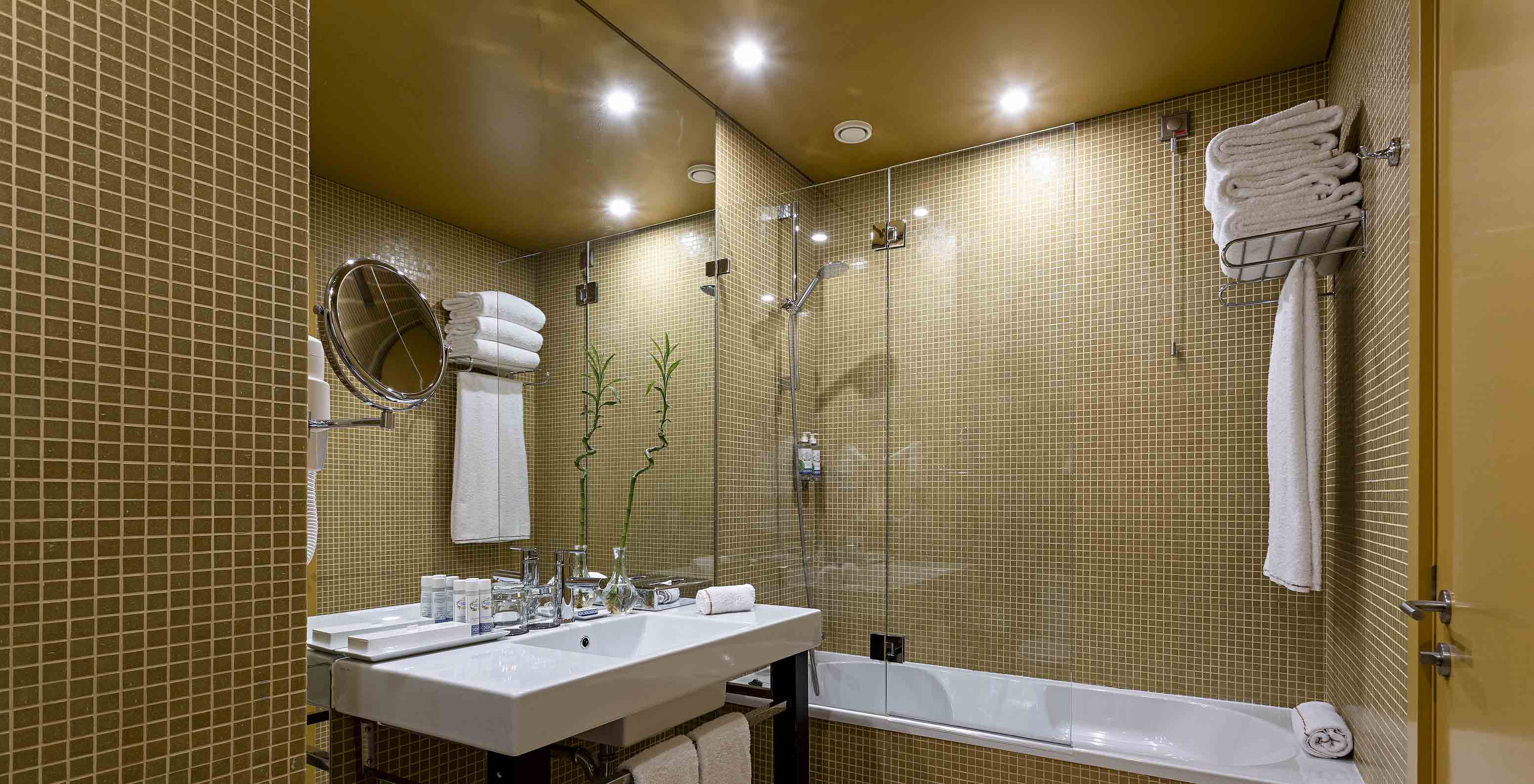 The Junior Suite has a bathroom with yellow tiles, a sink, and a bathtub