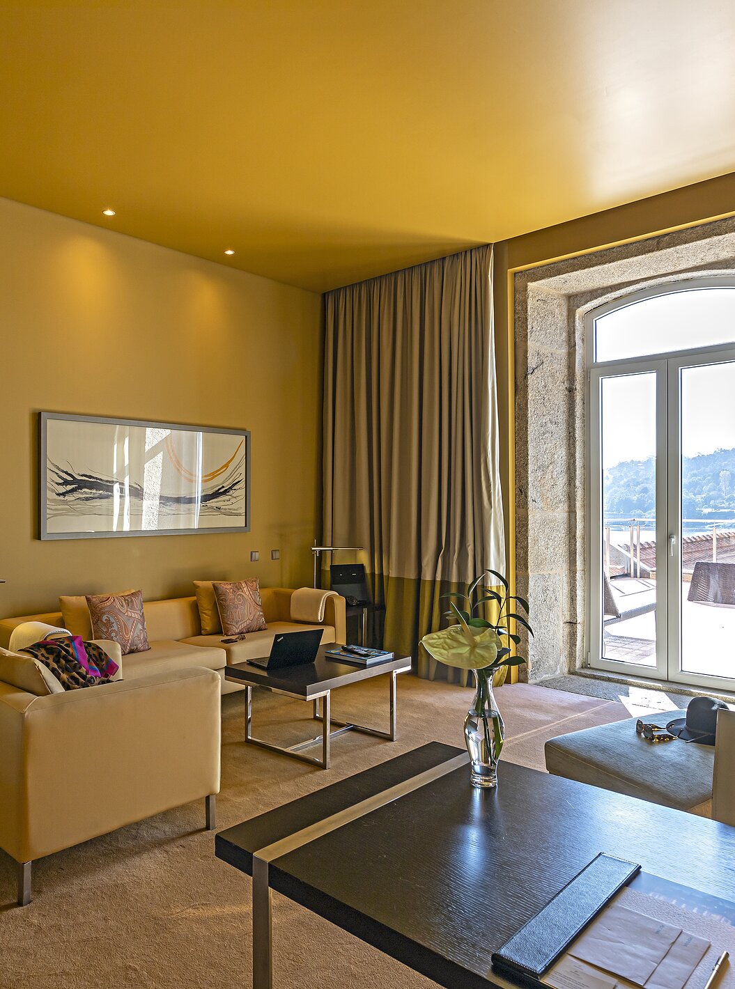 The Suite Nasoni has a living room with sofas, a desk, and a stone-framed window to the balcony