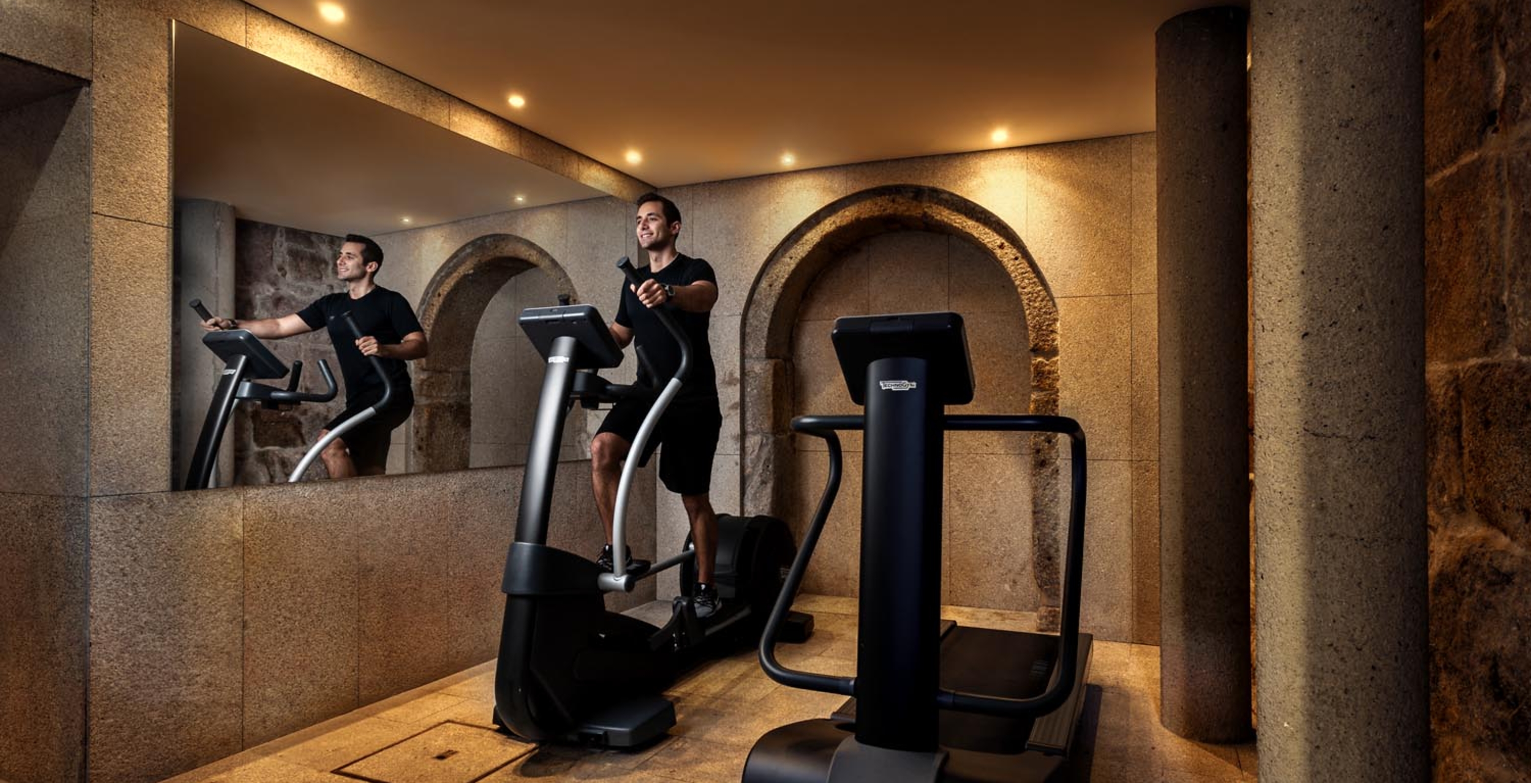 Person exercising on gym machines at Pestana Vintage Porto, a hotel at Praça da Ribeira in Porto