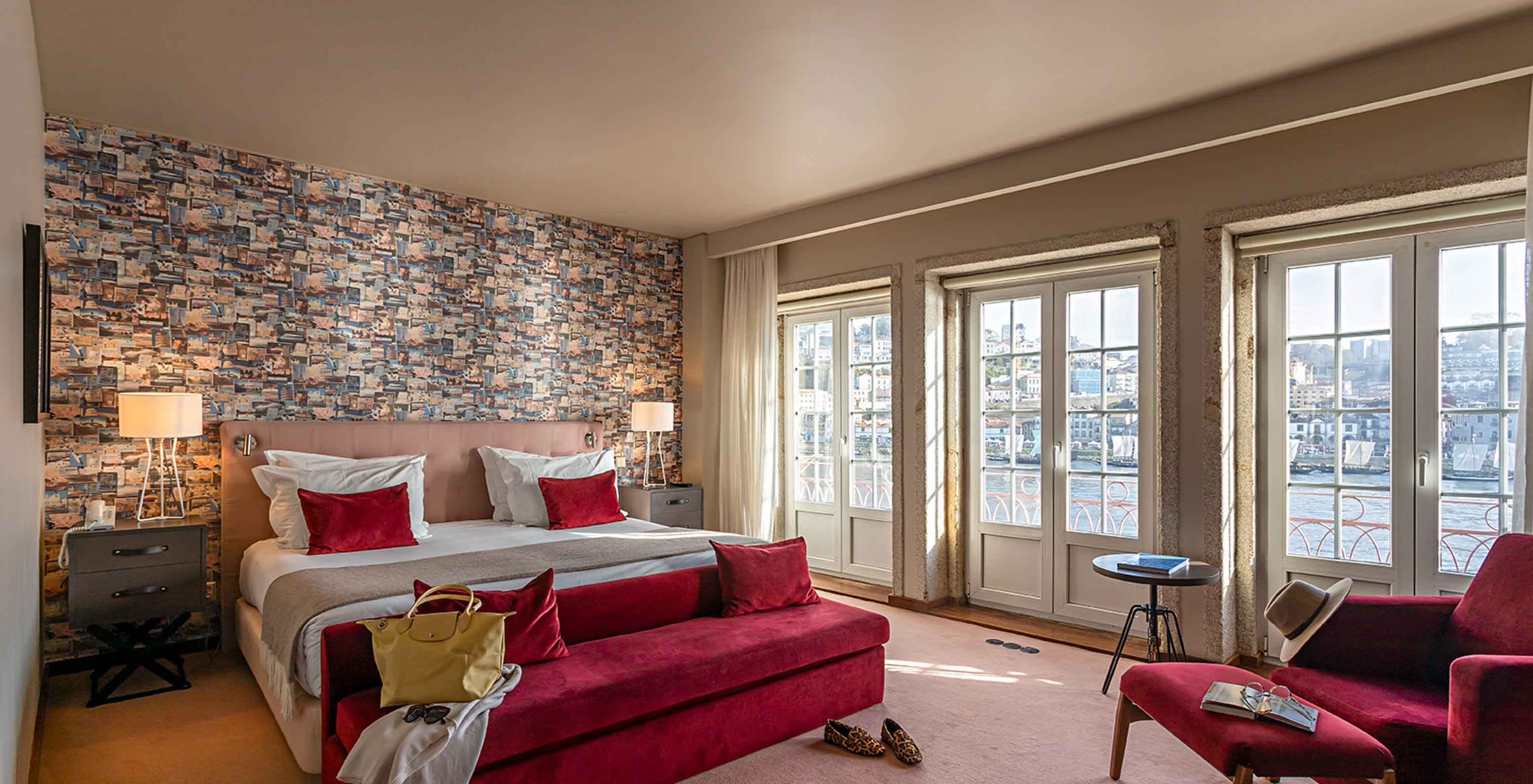 The Suite Grand View at Pestana Vintage Porto has a double bed, a red sofa and windows with a view of Porto