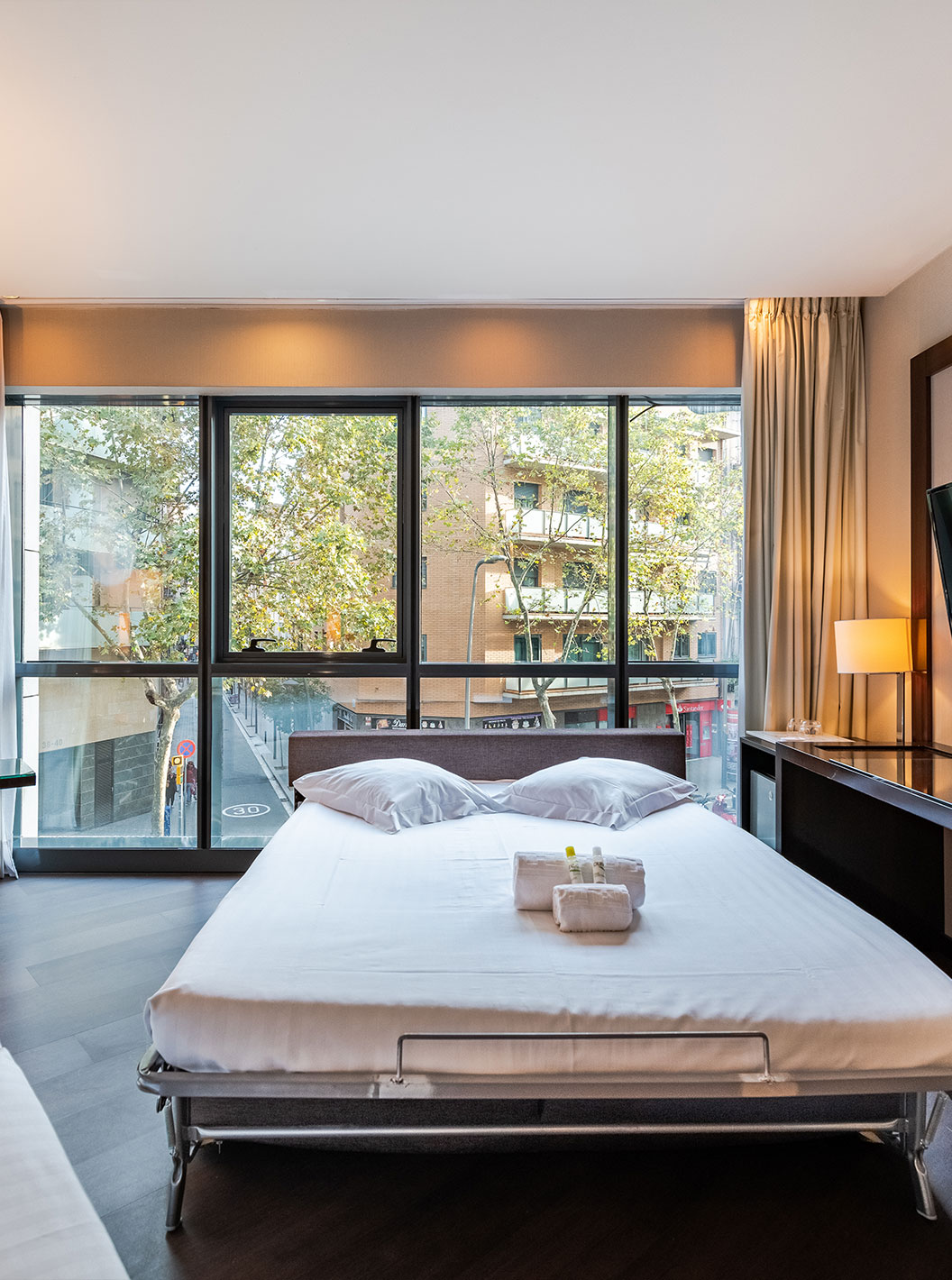 Superior Family room at Pestana Arena Barcelona has a TV and a window with a view of the city of Barcelona