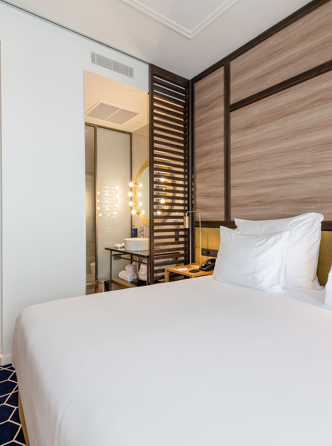 The Premium Grand Room with Balcony at Pestana CR7 Gran Vía Madrid has a double bed, wooden partition, and lighted mirror