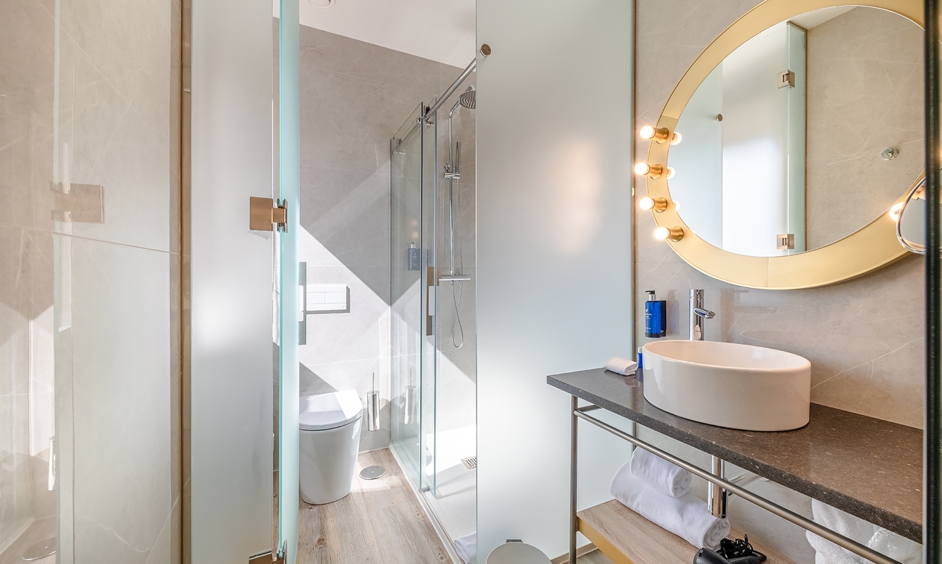 The Small Double Room at Pestana CR7 Gran Vía Madrid has a bathroom with a round mirror, toilet, and shower
