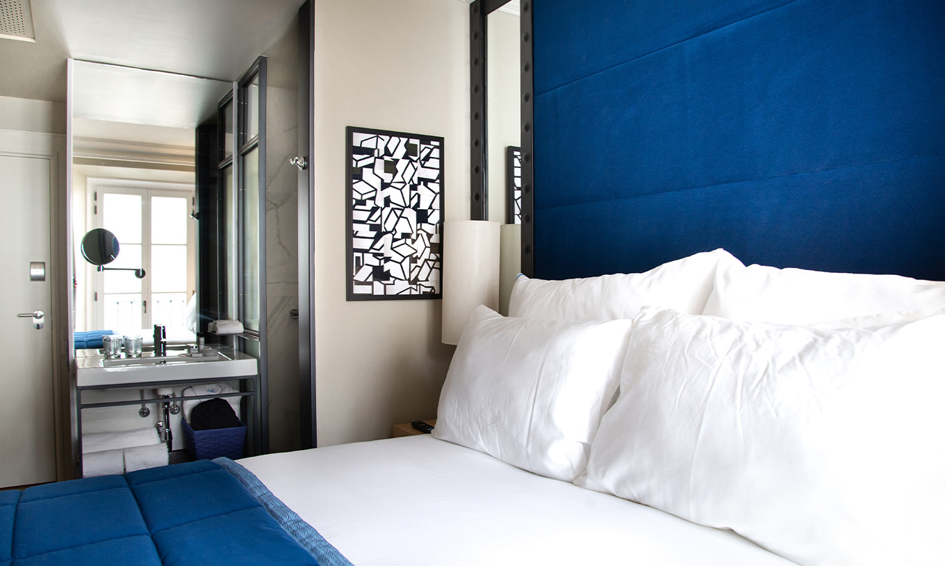 The Classic Room at Pestana Plaza Mayor Madrid has a double bed, a painting and bathroom with sink