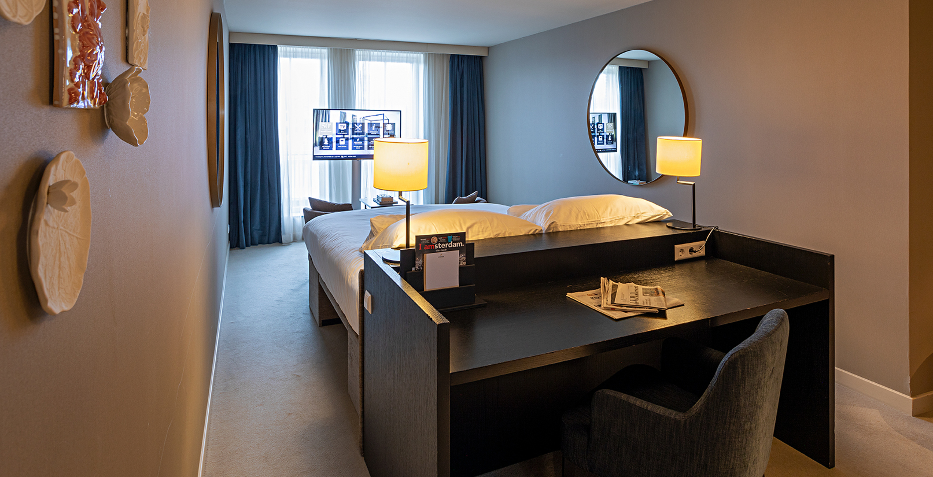 Superior - River View room at Pestana Amsterdam Riverside has a TV in front of the bed and a desk