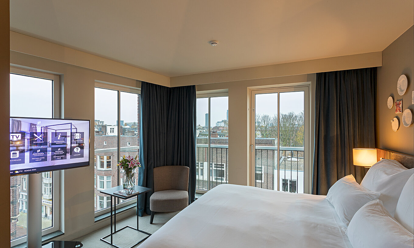Studio room at Pestana Amsterdam Riverside has a double bed, a lamp and windows overlooking the street