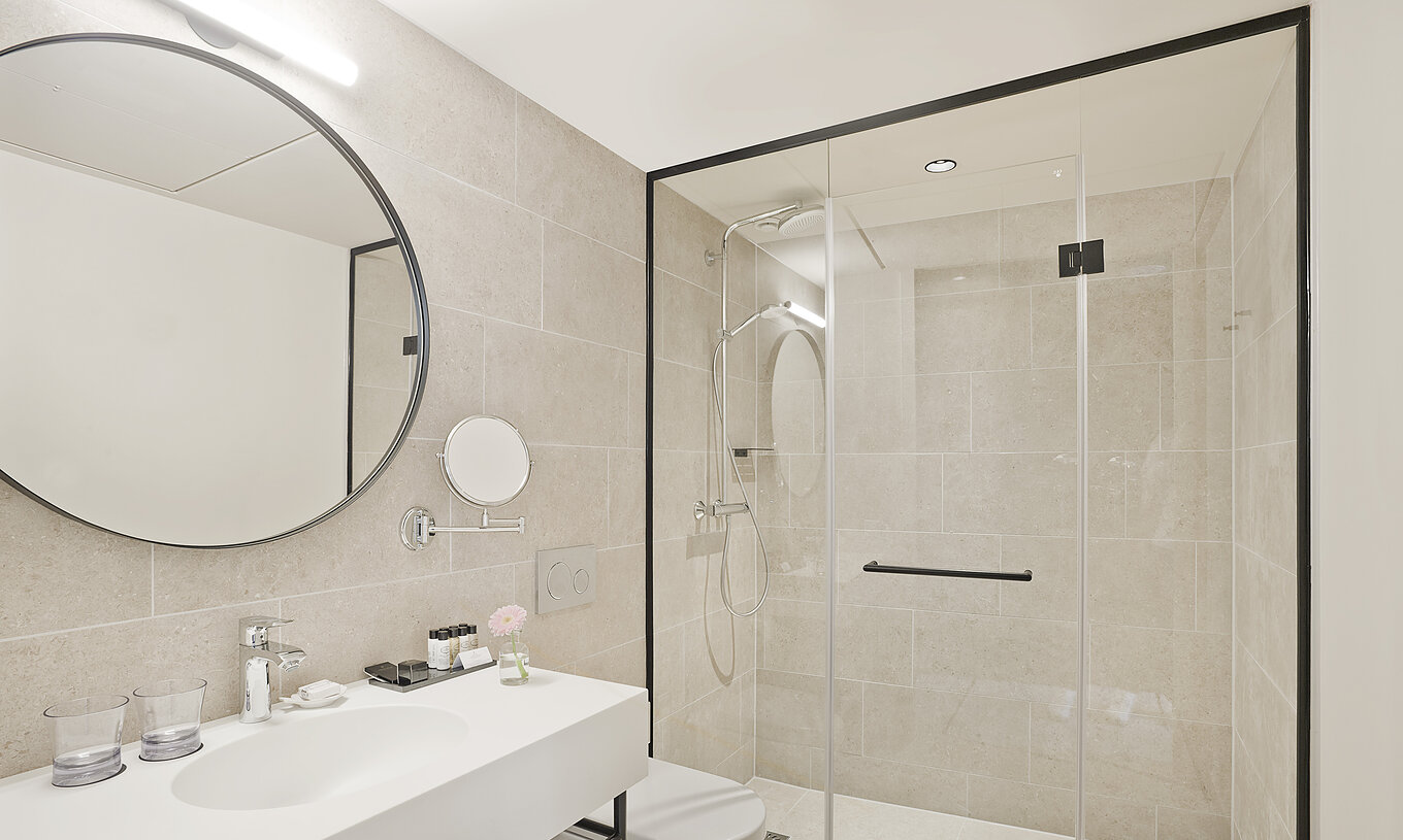 Executive - River View room at Pestana Amsterdam Riverside has a bathroom with mirror, sink, towels and shower