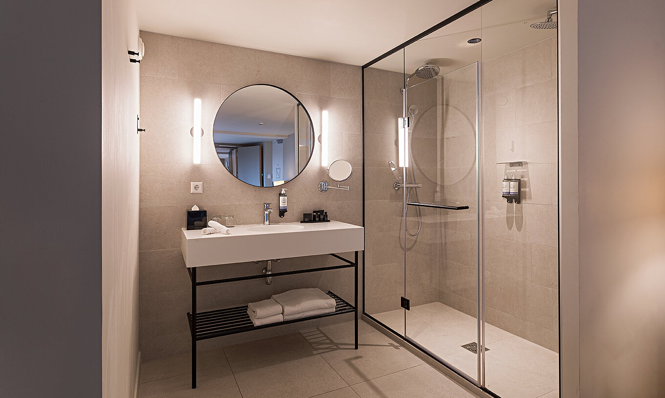 Executive Terrace room at Pestana Amsterdam Riverside has a bathroom with mirror, sink, towels and shower