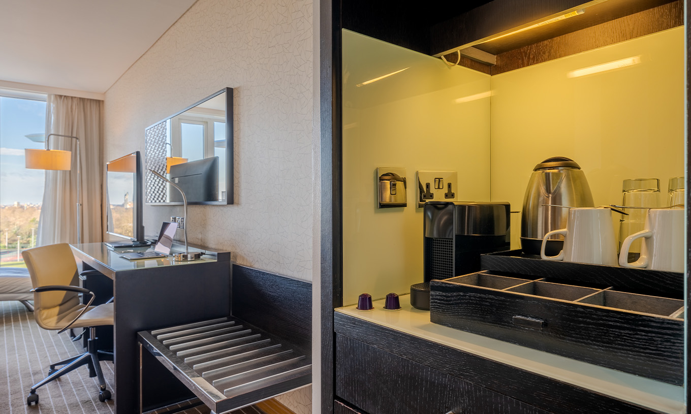 The Deluxe Premium King at Pestana Chelsea Bridge has a coffee and tea station, a desk with a TV, and a window with a view