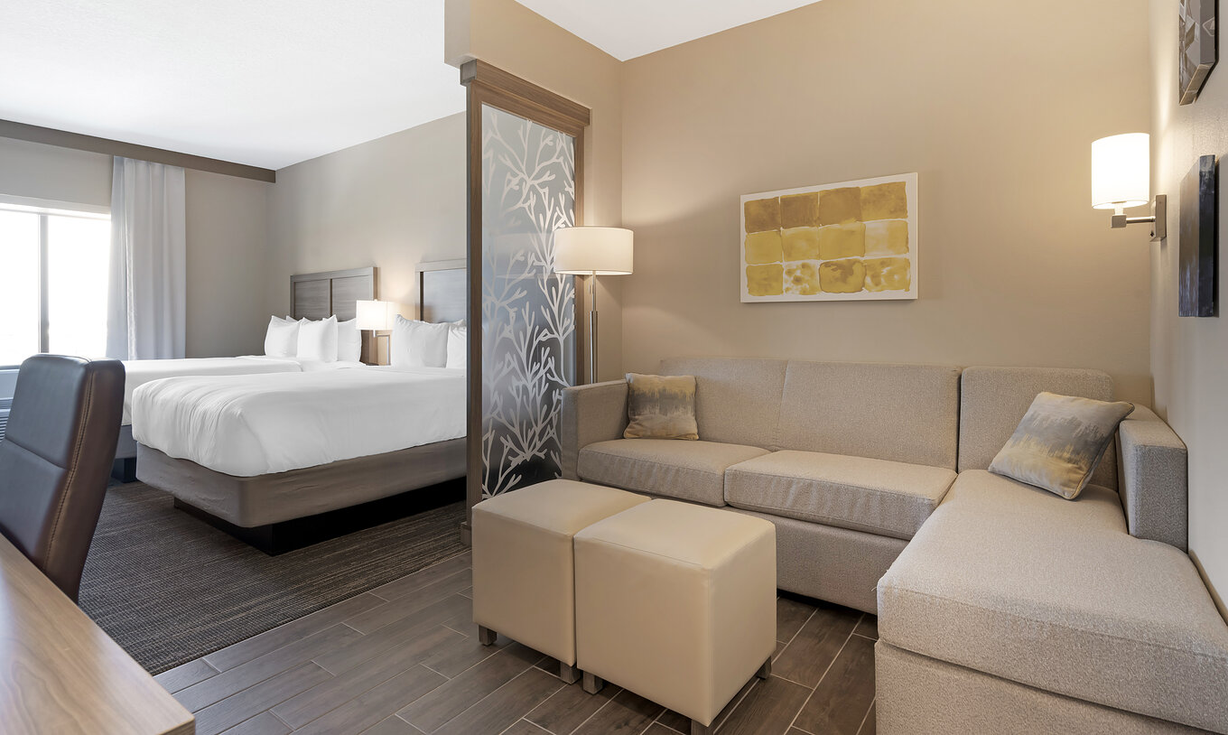 The Double Queen Suite at Pestana Orlando Suites Lake Buena Vista includes two double beds, a desk, sofa, and lamp