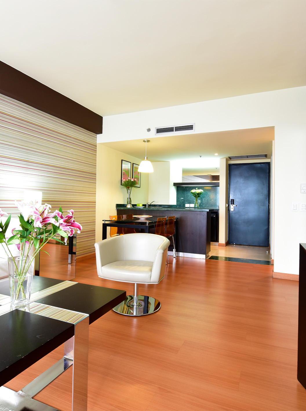 The King Junior Suite at Pestana Caracas has a living room with a comfortable white sofa, a side table, and a TV