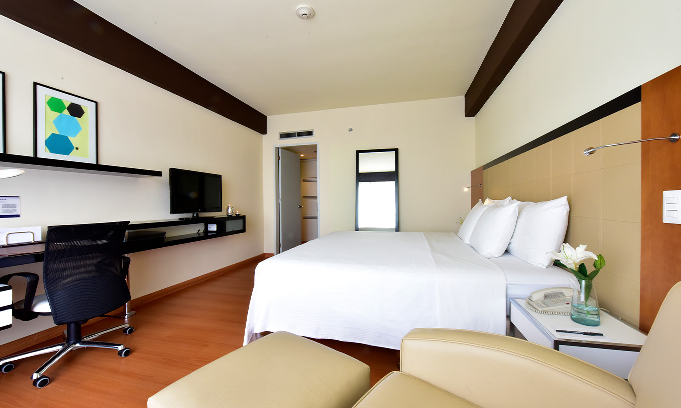 The Twin Superior Room at Pestana Caracas has a double bed, a mirror, a desk, and an armchair