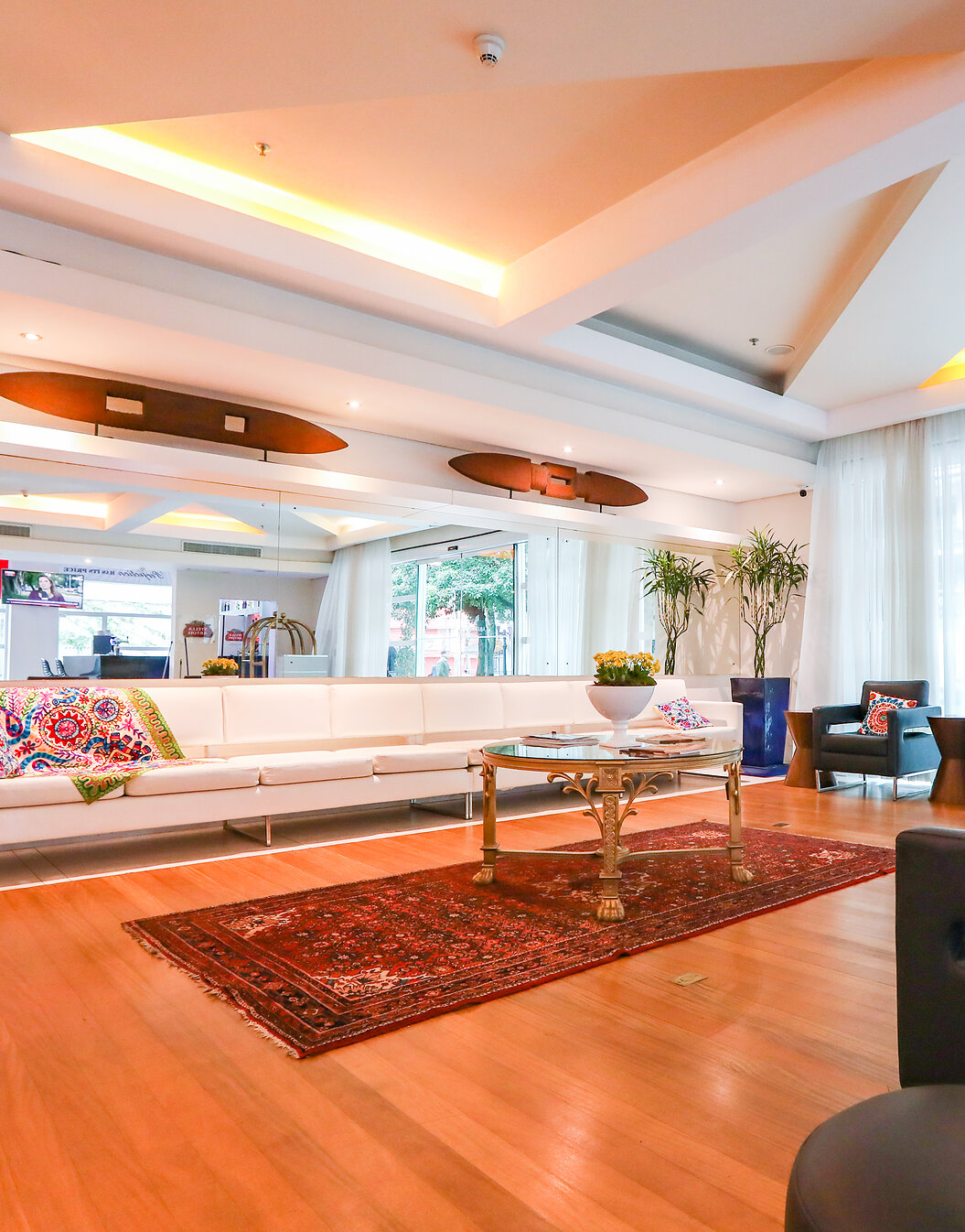Entrance of Pestana Curitiba with 4 armchairs and a long white sofa with colorful cushions and a coffee table